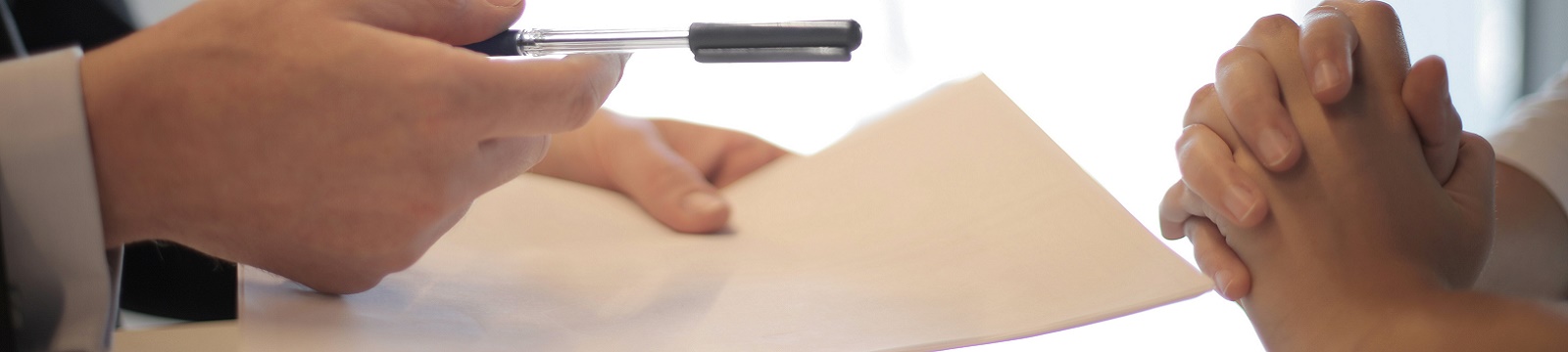 Man handing a contract to a woman to sign